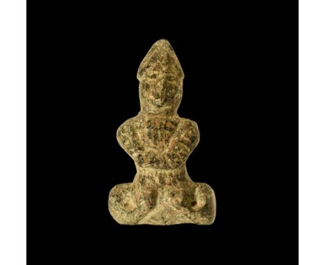 3rd-2nd millennium BC. A soapstone figure of a seated male wearing a conical helmet, arms crossed at chest over mail coat, an