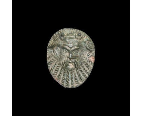 1st century BC-2nd century AD. A convex mount of the face of Silenus with ivy-leaf wreath to the brow and radiating braided b