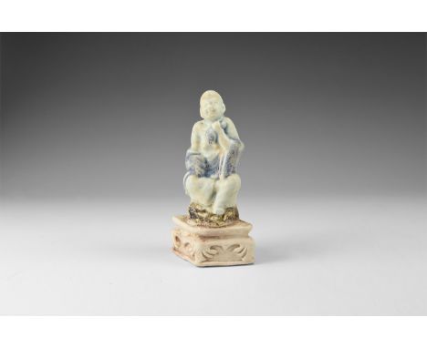 Qing Dynasty, 1644-1912 AD. A porcelain figure of the fasting Buddha seated on a dark brown rock on a lozenge shaped base wit
