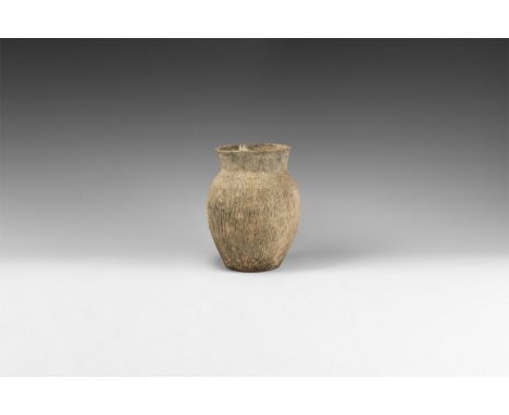 3rd millennium BC. A biconvex ceramic jar with flared rim, ridged leather texture to the body and shoulder.   777 grams, 16cm