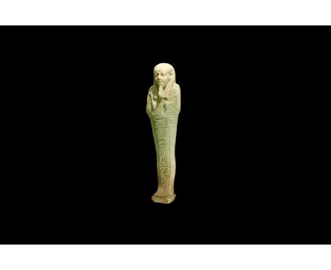 Late Period, 664-332 BC. A pale blue glazed composition shabti with tripartite wig, false beard, agricultural tools in the cr