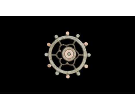 1st-2nd century AD. A bronze and enamelled wheel brooch with lobe extensions, openwork rosette body and raised boss to the ce