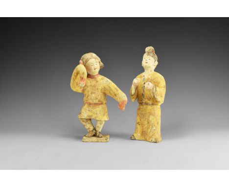 Tang Dynasty, 618-907 AD. A pair of terracotta entertainers consisting of: one of a drummer (?) wearing long yellow robes bel