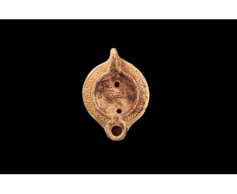 2nd century AD. A ceramic oil lamp with shoulder decorated with chevron pattern and dish with a walking peacock; wide round n