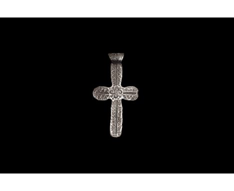 5th-9th century AD. A flat-section silver cruciform pendant with rounded arms and applied loop, rows of punched triangles wit