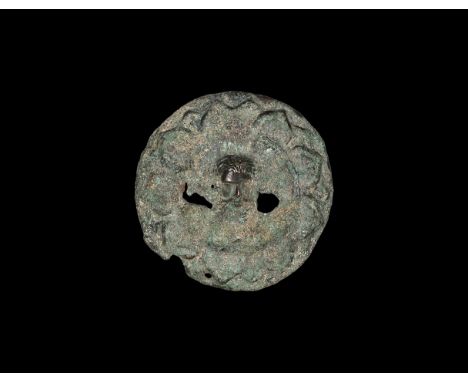 2nd-3rd century AD. A convex discoid plaque with band of overlapping lotus leaves, central facing head of a bodhisattva in hi