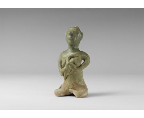 14th-16th century AD. A green-glazed ceramic figurine of a nude seated female with bun to the back of the head, suckling a ba