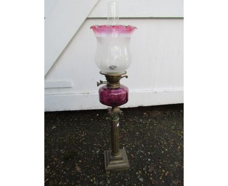 Oil lamp with cranberry coloured glass font, tulip shade and brass base