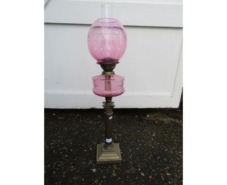 Oil lamp with brass base cranberry coloured font and globe shade