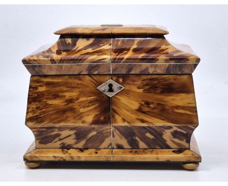 A Regency blonde tortoiseshell tea caddy, c.1815, of sarcophagus form with white metal stringing and escutcheon and horn face
