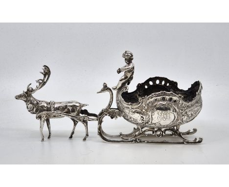 A German silver novelty table ornament, fashioned as a putti driving a sled pulled by a reindeer, impressed marks to base inc