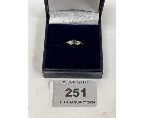 A 9ct three stone emerald and diamond ring. 1.3g gross. Size K.