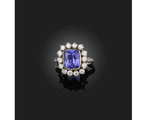 A tanzanite and diamond ring, of cluster design, collet-set with a cushion-shaped tanzanite stated to weigh 4.83 carats, to a