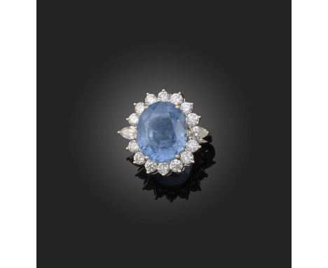 A sapphire and diamond cluster ring, the oval-cut sapphire weighing 13.16cts within a surround of pear-shaped and brilliant-c