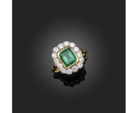 An emerald and diamond ring, of cluster design, set with a step-cut emerald weighing approximately 1.40 carats, within a bord