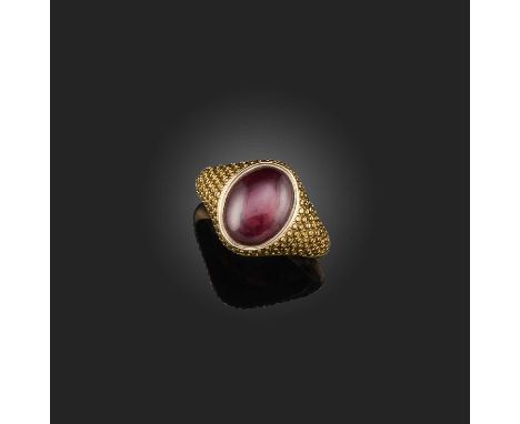 A cabochon garnet ring, circa 1815, set with a cabochon garnet in a closed setting, within a gold mount engraved with spiral 
