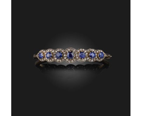 A sapphire and diamond bangle, early 20th century, of hinged design, the front set with a line of circular-cut sapphires with