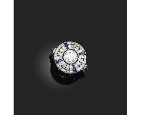 A diamond and sapphire ring, designed as a geometric cluster of Art Deco inspiration, centring on a brilliant-cut diamond wei