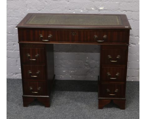 A hardwood twin pedestal desk of small proportions with green leather inset top.