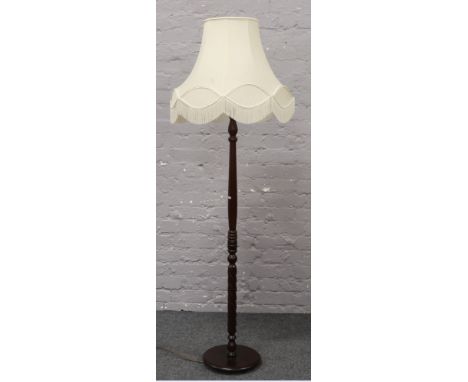 A turned mahogany standard lamp with cream shade.