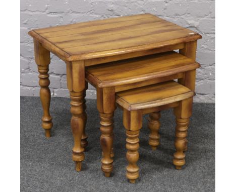 A nest of three hardwood bow front occasional tables raised on turned legs.