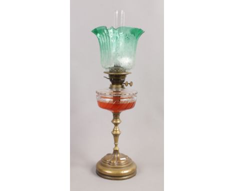 An Arts and Crafts brass based oil lamp with cut glass font and green tinted glass shade.Condition report intended as a guide
