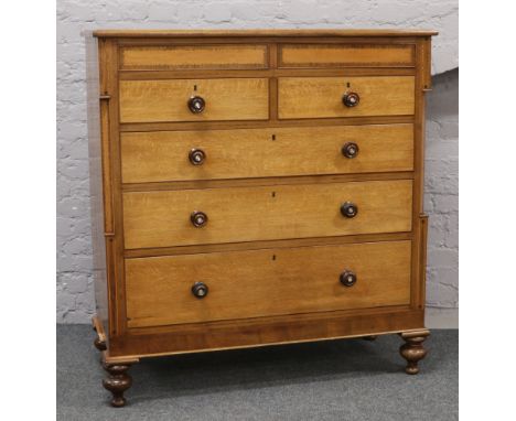 A Victorian carved oak and mahogany inlaid chest of two drawers with a pair of drawers concealed in the frieze, raised on bun