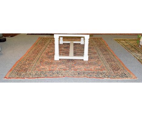 A Sultanabad carpet, West Iran, circa 1920, the soft terracotta field with an allover design of flower heads and vines, enclo