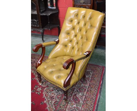 A green leather button back library armchair, mahogany scroll arms, turned forelegs, brass casters, 97cm high