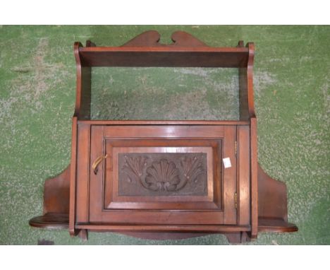 A mahogany wall cabinet, single shelf above carved panel doored cupboard, circa 1920.