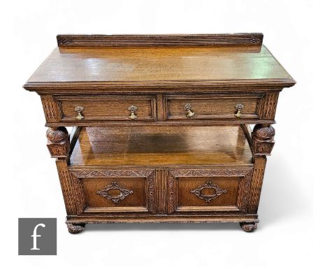 A 1930s Jacobean style carved oak two tier buffet, the moulded edge top over two frieze drawers below a ledge back over a cup