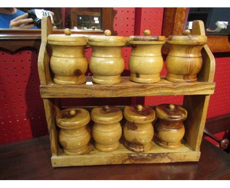 A two tier wooden spice rack with eight turned wood lidded spice jars