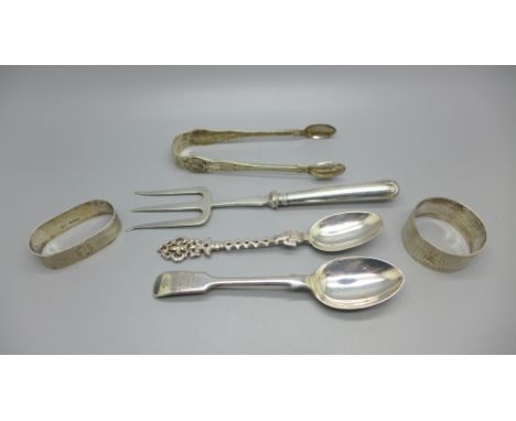 A collection of silver; sugar bows, two spoons and two napkin rings, 125g, and a fork with silver covered handle 