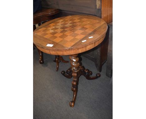 A Victorian pedestal games table with a veneered chess board top raised on a barley twist column and scrolled tripod base, 25