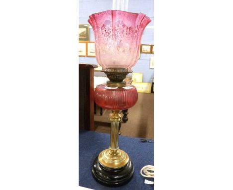 A 19th Century oil lamp, the brass Corinthian column with ruby glass reservoir and ruby/pink glass shade with floral decorati