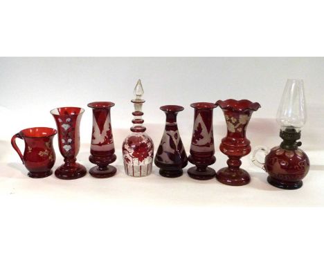 A collection of 19th Century cranberry glass wares including a small lamp with fruiting vine design, vase with panels of pain