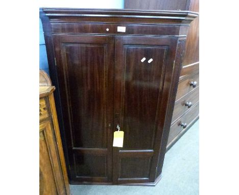 A Georgian mahogany corner cabinet with two panelled doors opening to a painted interior with shaped shelves, 121cm high (Ite