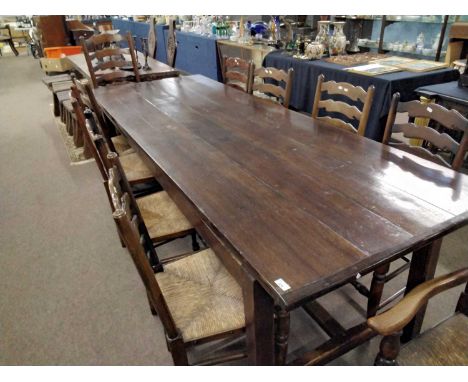 A large oak refectory dining table with H formed stretcher together with a set of ten rush seat and ladder back dining chairs