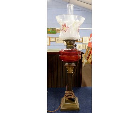 A late 19th Century oil lamp with Corinthian column with ruby glass reservoir and white shade with painted floral decoration,