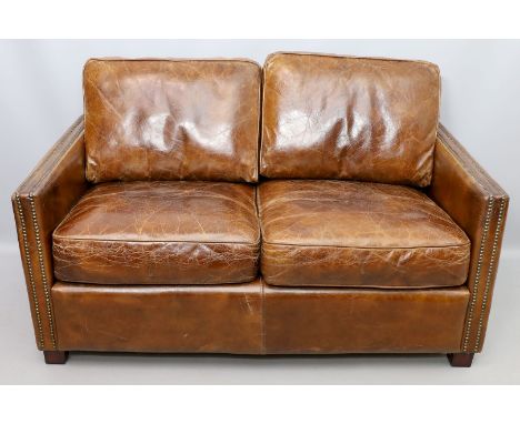 Sofa, 2-Sitzer. Braunes Leder. Armstützen vernietet. Gebrauchsspuren, Kratzer, berieben. Ende 20. Jh. Ca. 69x 138x 83 cm.