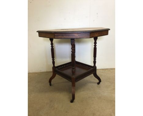 An octagonal inlaid Edwardian table with lower galleried shelf on metal and ceramic castors. W:76cm x D:76cm x H:74cm