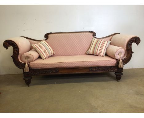 A heavily carved mahogany Victorian scroll arm sofa on brass castors. W:220cm x D:70cm x H:90cm