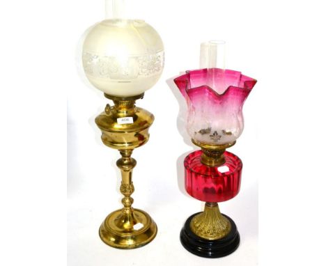 Two oil lamps with glass shades, one being a cranberry glass oil lamp 