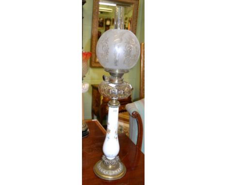 A Victorian oil lamp with floral painted glass upright and a clear glass reservoir, with etched shade 