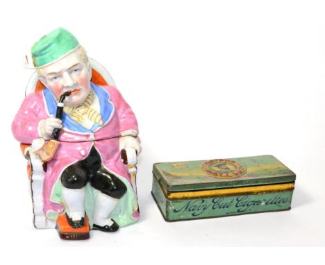 A German ceramic figural tobacco jar in the form of a seated gentleman smoking a pipe, with a Players navy cut tin (2)