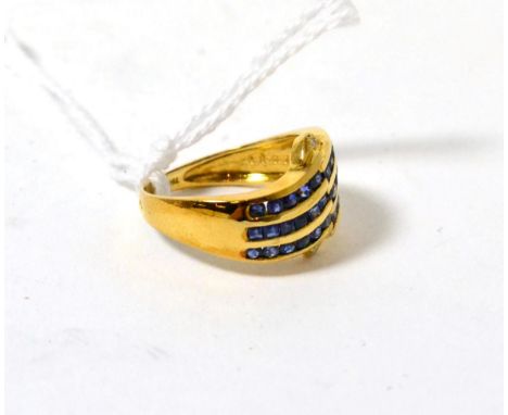 A sapphire and diamond ring, three rows of step cut sapphires in yellow channel settings between two round brilliant cut diam