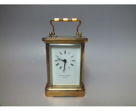A MODERN MATTHEW NORMAN CARRIAGE CLOCK, the brass case with four glass panels and visible escapement to the top, case H 11 cm