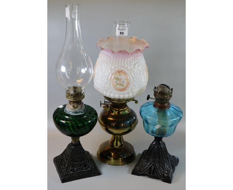 Two early 20th century single  burner oil lamps with coloured reservoirs, on cast metal bases. Together with another double o