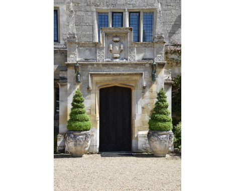 A PAIR OF LARGE COMPOSITION STONE PLANTERS PLANTED WITH SPIRAL CUT CONICAL BOX MODERN The planters with mask decoration withi