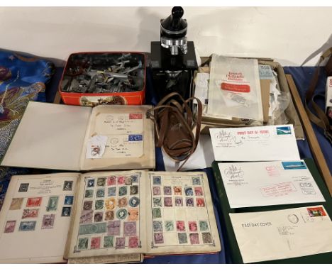 A collection of stamp albums together with first day covers including one posted aboard the QE2, a microscope and model plane
